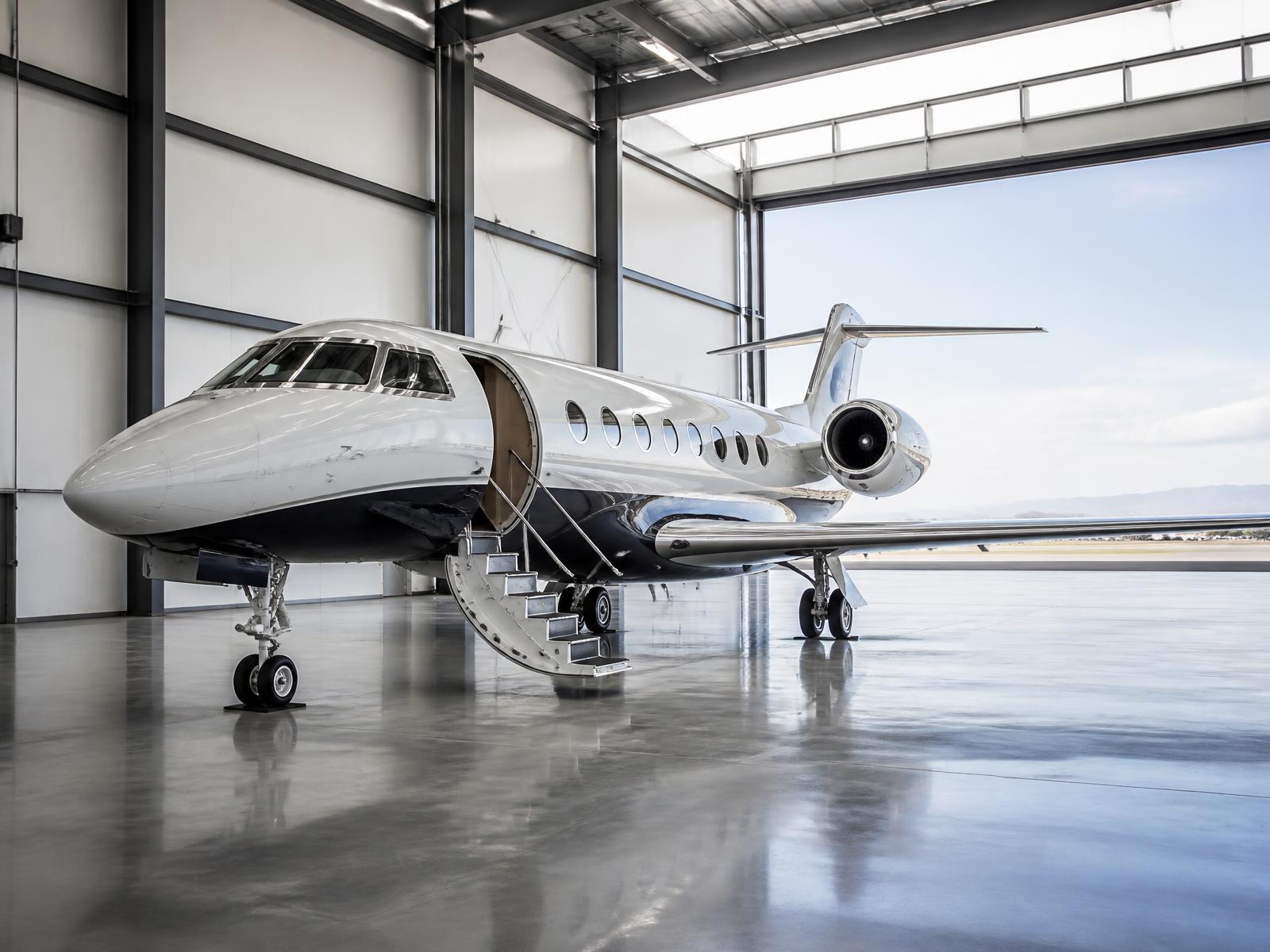 Aeronave executiva em hangar com portão aberto para a pista