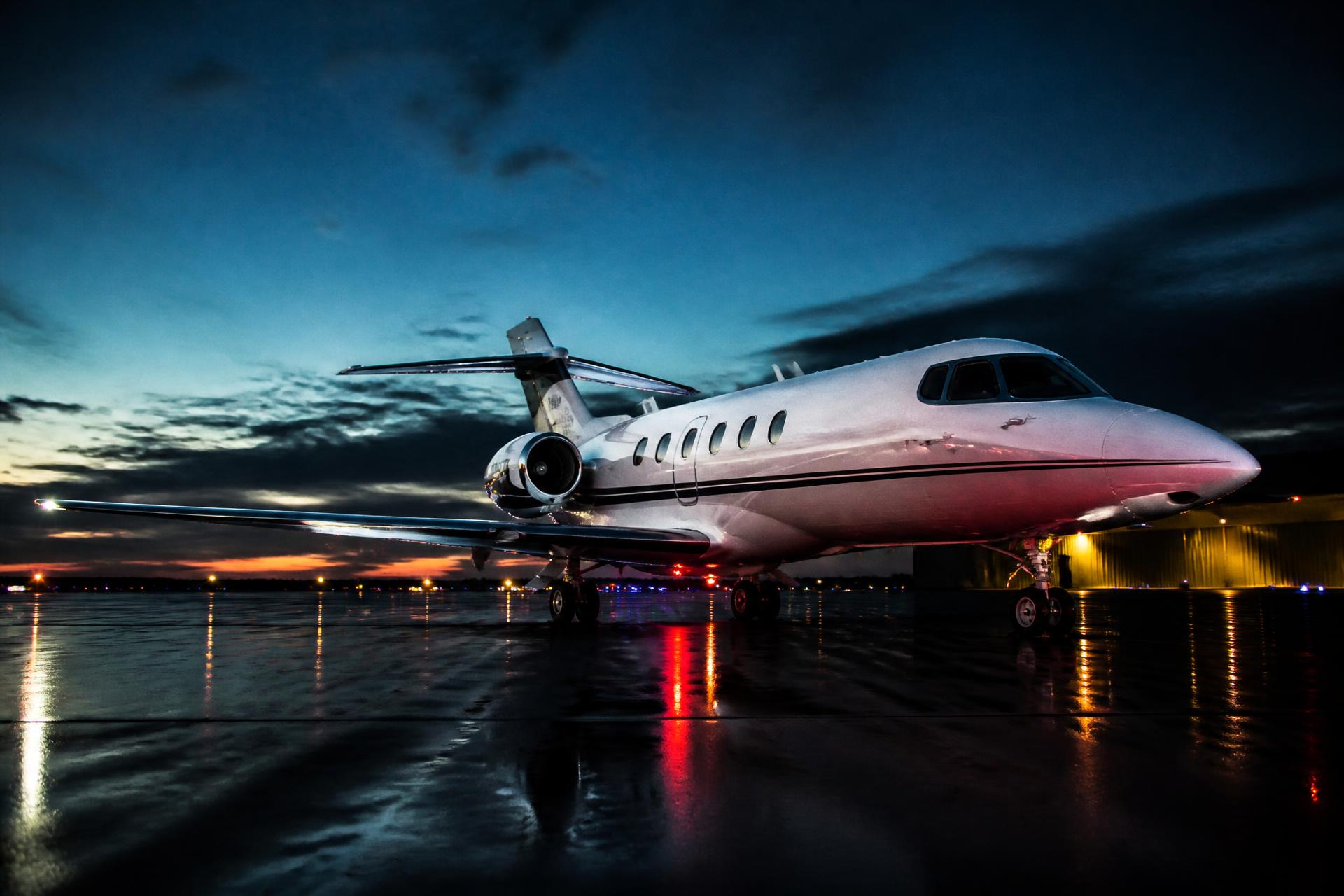 Jato executivo posicionado no pátio de um aeroporto ao entardecer